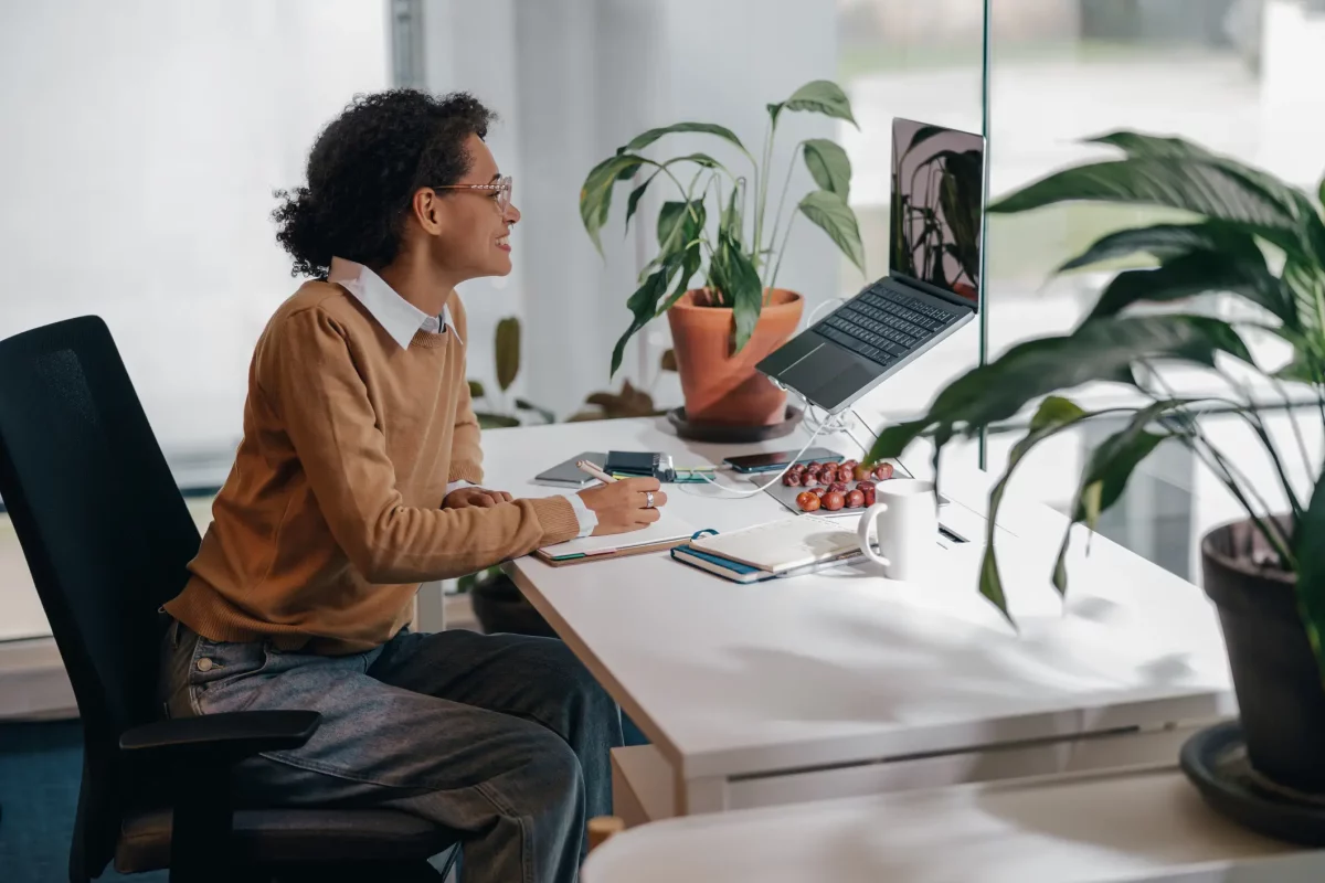 How to setup video conferencing: Female freelancer have video conference with client and making notes sitting in cozy coworking